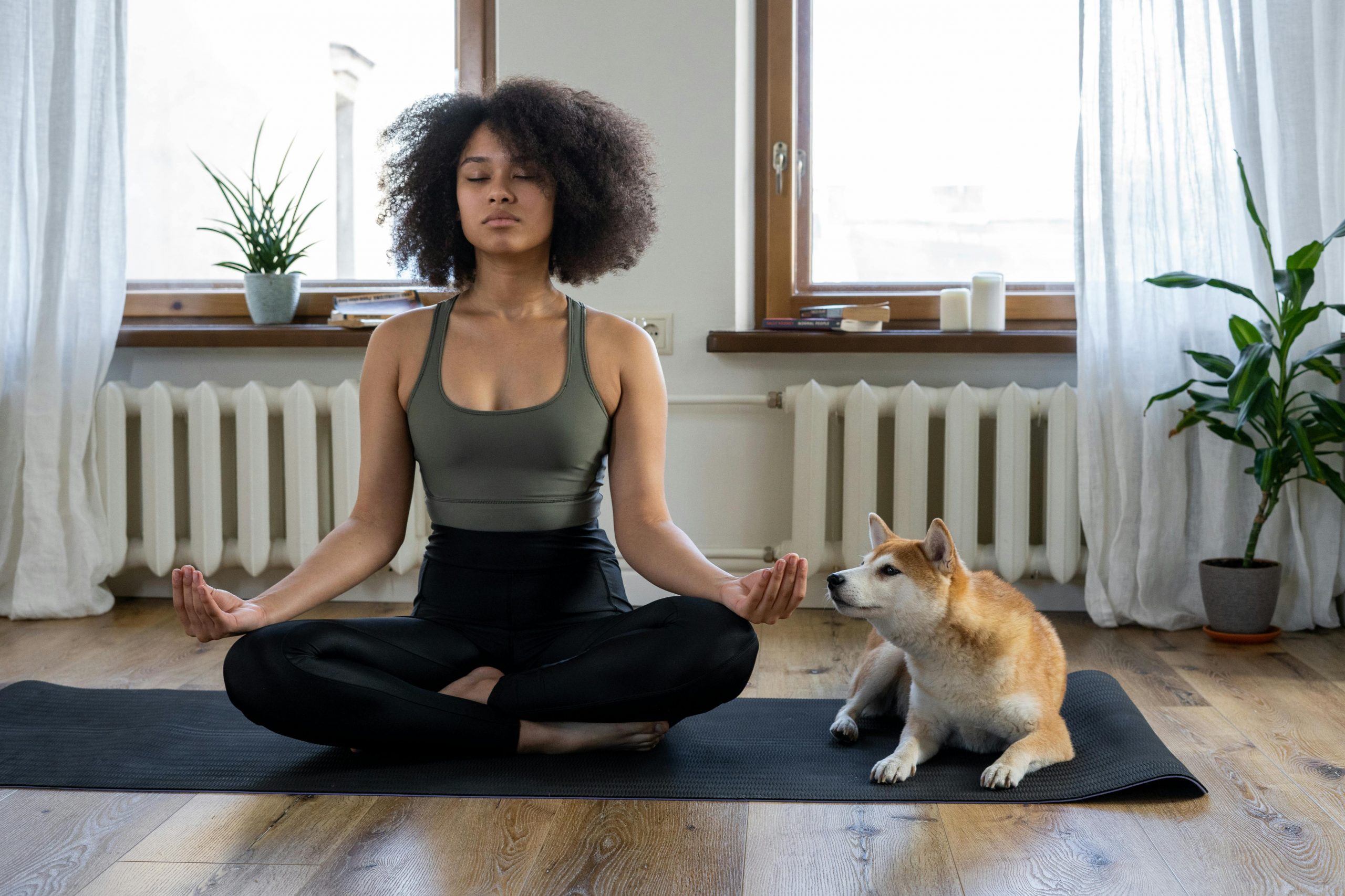 woman meditating on a yoga mat beside her dog