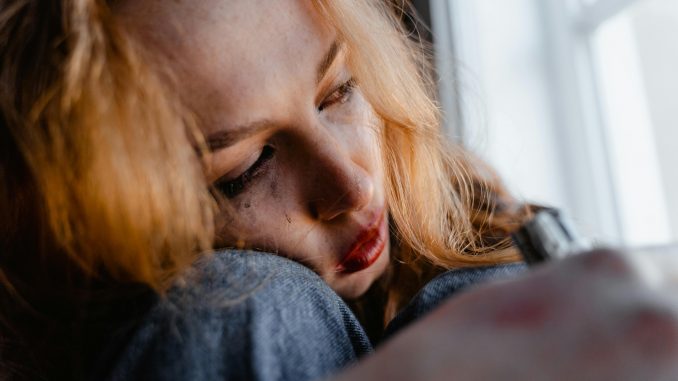 pexels-mart-production-7279113 woman crying while looking out a window, with smudged eyeliner on her face