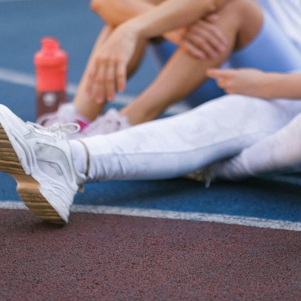 female athletes sitting on a track field, with water-filled tumblers beside them